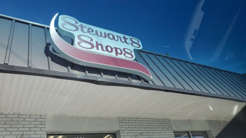 Sign for Stewart's Shops on a building under a clear blue sky.