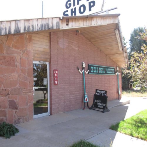 A gift shop with a sign reading "Open" and decorative elements, set in a sunny outdoor environment.