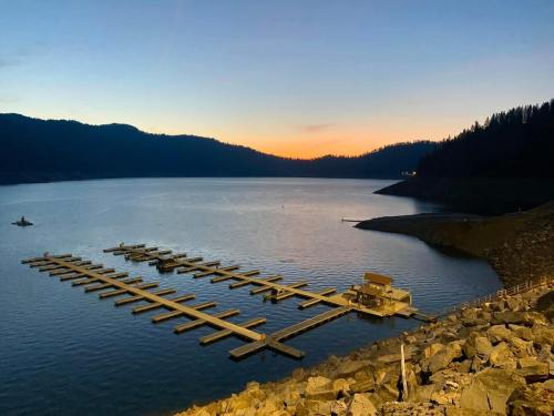 A serene lake at sunset, featuring a wooden dock and mountains in the background, with calm waters reflecting the sky.