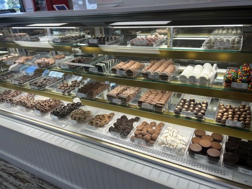 A display case filled with various chocolates, cookies, and confections in an assortment of shapes and colors.