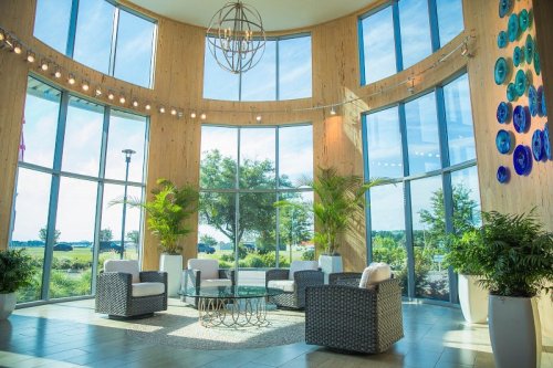 Bright, modern lounge with large windows, stylish furniture, and greenery, creating a welcoming atmosphere.