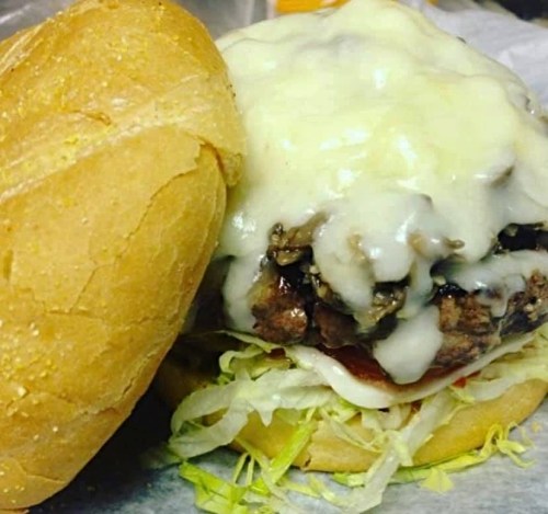 A close-up of a burger with melted cheese, lettuce, and sauce, nestled in a soft bun.