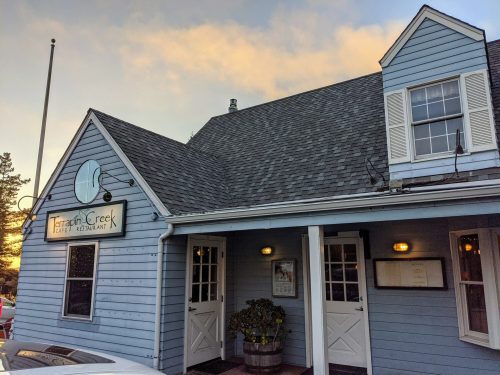 A blue wooden building with a sloped roof, featuring a sign for "Terrace Creek Café & Restaurant" and two entrance doors.