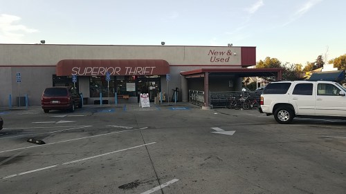 Exterior of Superior Thrift store with a sign reading "New & Used," surrounded by parking spaces and bicycles.