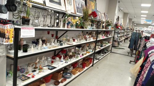 A store aisle displaying shelves filled with various decorative items, including glassware, figurines, and framed art.
