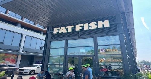 Exterior of a restaurant named "Fat Fish," featuring large signage and people seated outside.