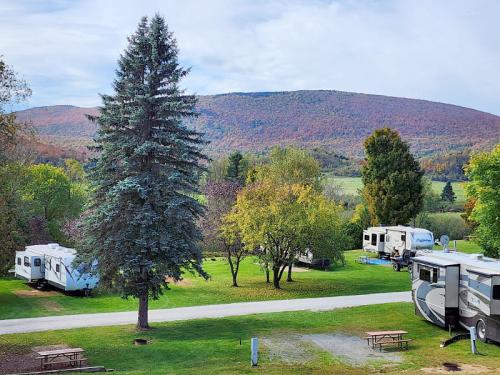 A scenic view of a campground with RVs, trees, and mountains in the background, showcasing autumn foliage.