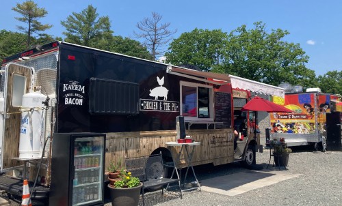 A food truck named "Chicken & the Pig" parked alongside another colorful food truck in a sunny outdoor setting.