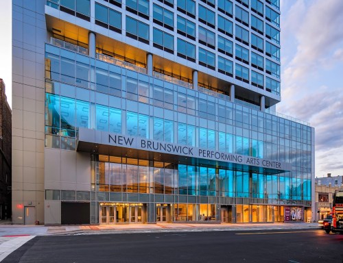 Modern building exterior of the New Brunswick Performing Arts Center with large glass windows and a sleek design.
