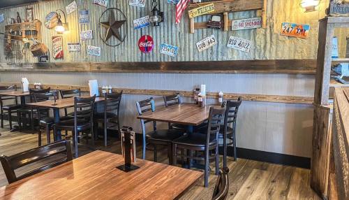 Cozy restaurant interior with wooden tables, black chairs, and vintage decor including license plates and Americana.