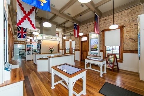Interior of a bright, spacious room with wooden floors, flags hanging, and display tables.