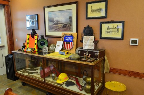 Display case featuring vintage railroad memorabilia, including lanterns, helmets, and framed train artwork.