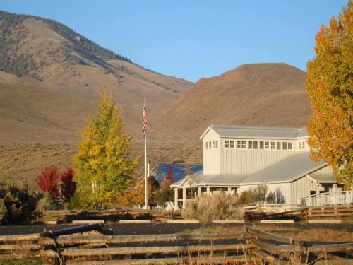 A rustic building with an American flag, surrounded by colorful trees and mountains in the background.