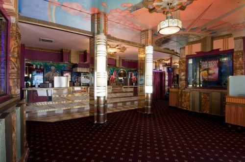 Art Deco-style interior of a vintage theater lobby with ornate details and colorful murals.