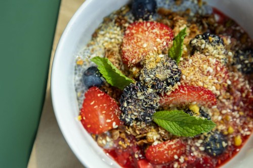 A bowl of chia pudding topped with strawberries, blueberries, granola, and mint leaves.