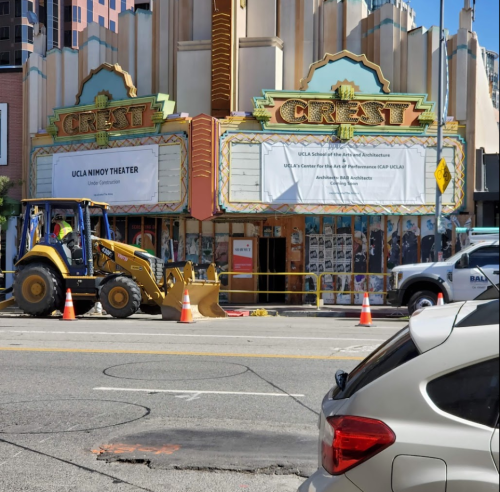 Construction equipment in front of the Crest Theater, with banners covering the marquee and traffic cones on the street.