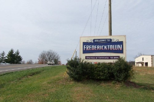 Welcome sign for Fredericktown, with a grassy area and road in the background.