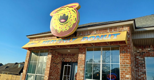 A brick storefront with a large, colorful donut sign reading "Heavenly Donut" and an "Open" neon sign in the window.