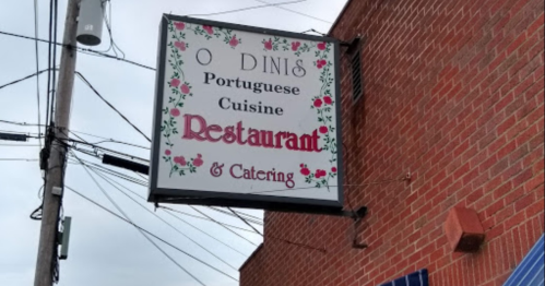 Sign for "O Dinis" restaurant featuring Portuguese cuisine, with floral decorations and catering services listed.