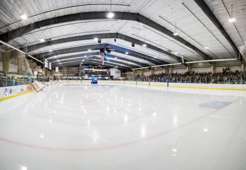 A spacious ice rink with a Zamboni on the ice and a large crowd in the stands, ready for a hockey game.