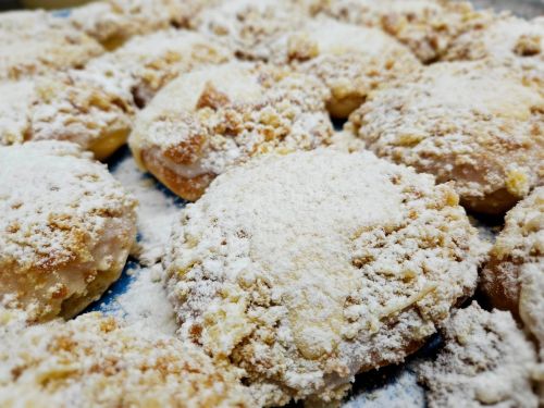 A close-up of powdered sugar-dusted pastries arranged on a tray, showcasing their crumbly texture.
