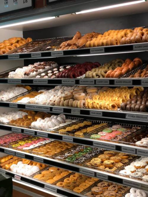 A display case filled with a variety of colorful donuts, including glazed, chocolate, and specialty flavors.