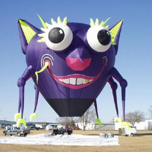 A colorful hot air balloon shaped like a cartoonish cat with large eyes and playful features against a clear blue sky.