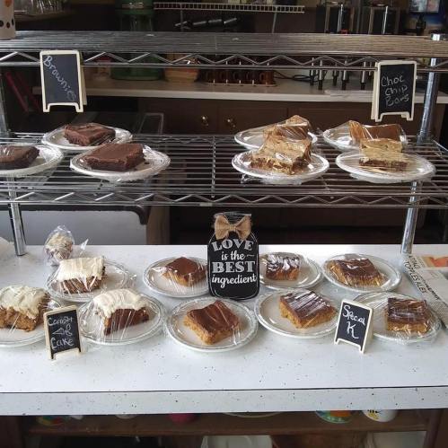 A display of assorted baked goods, including brownies, chocolate chip cookies, and carrot cake, on white plates.