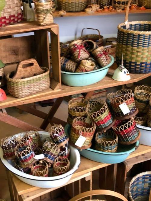 A variety of woven baskets displayed on wooden shelves, featuring colorful patterns and different sizes.