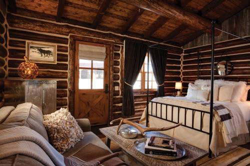 Cozy log cabin interior featuring a bed, sofa, wooden decor, and warm lighting.