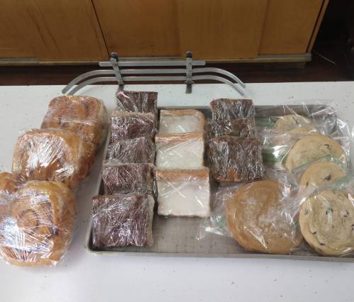 A tray of assorted baked goods, including wrapped pastries, slices of bread, and cookies.