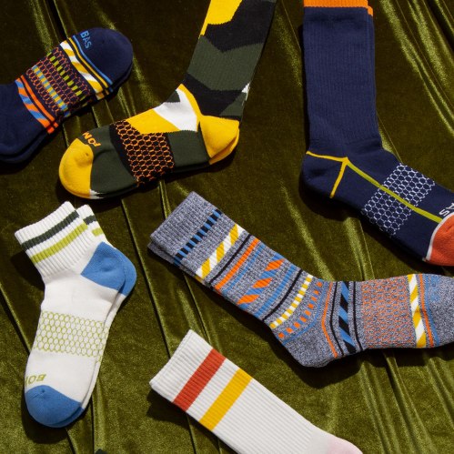 A variety of colorful socks displayed on a textured green surface, featuring different patterns and designs.