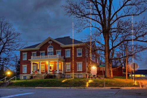 Historic brick building illuminated at dusk, adorned with holiday lights and surrounded by bare trees.
