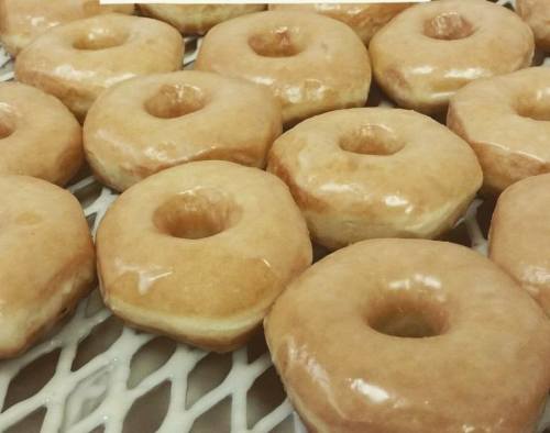 A close-up of freshly glazed donuts arranged on a cooling rack.