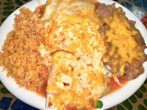 A plate of enchiladas topped with cheese, served with rice and refried beans.