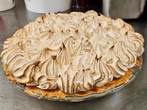 A freshly baked pie topped with golden-brown meringue swirls on a flaky crust.