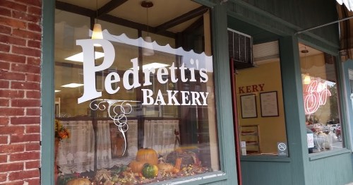 A bakery storefront with the sign "Pedretti's Bakery" and decorative pumpkins in the window.