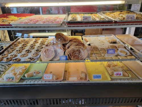 A display case filled with various baked goods, including cookies, pastries, and sweet treats.