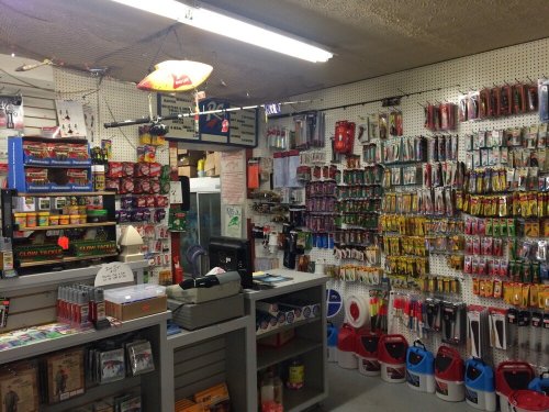 A well-stocked fishing supply store with various lures, tackle, and accessories displayed on the walls and shelves.