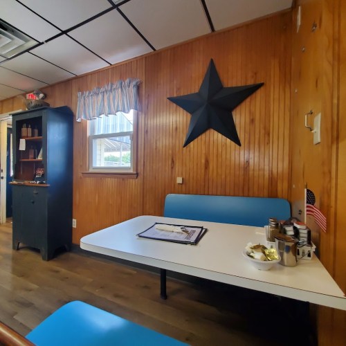 A cozy room with wooden walls, a blue table, and a star decoration, featuring a small American flag and menu on the table.