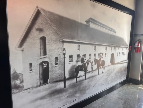 Black and white historic photo of a building with two people on horseback in front.