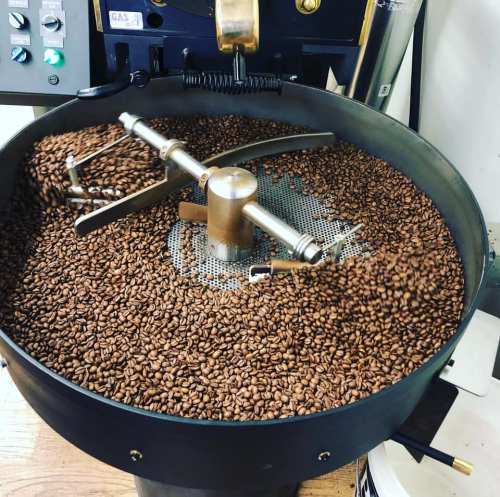 A coffee roaster filled with freshly roasted coffee beans, with a stirring mechanism in the center.