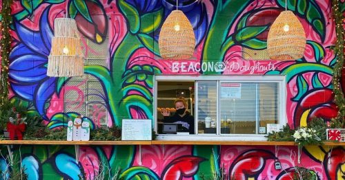 Colorful mural backdrop with a donut stand, featuring hanging lights and festive decorations.