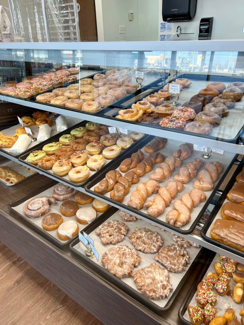 A display case filled with various types of donuts and pastries, including glazed, frosted, and sprinkled options.
