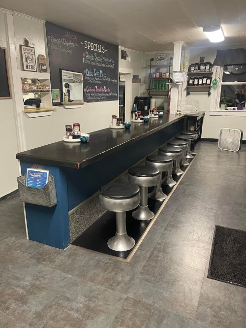 A diner interior featuring a long counter with metal stools, a chalkboard menu, and a cozy atmosphere.
