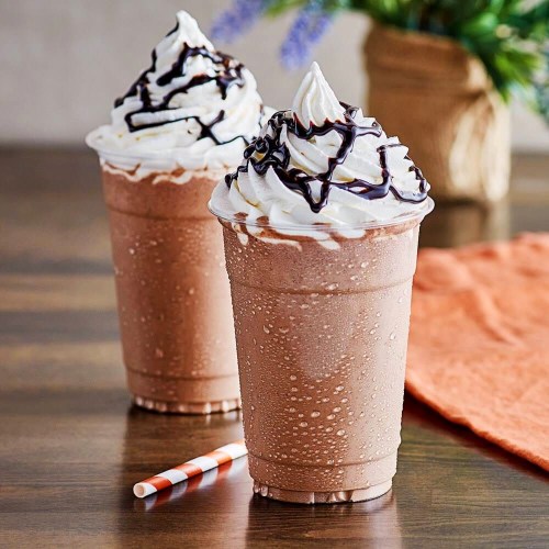 Two frosty chocolate milkshakes topped with whipped cream and chocolate drizzle, served in clear cups with a straw.