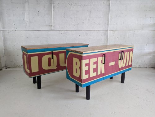 Two vintage-style cabinets with colorful signage reading "LIQUOR" and "BEER-WINE," set against a white wall.