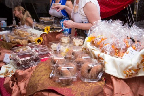 A table filled with various baked goods and treats, including cakes, cookies, and packaged snacks, decorated with flowers.