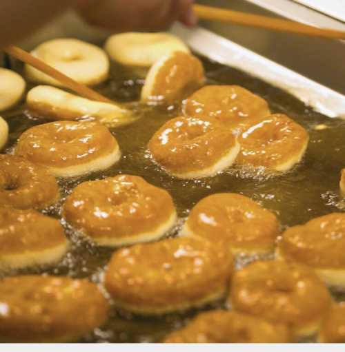 Freshly fried donuts bubbling in hot oil, golden brown and ready to be served.