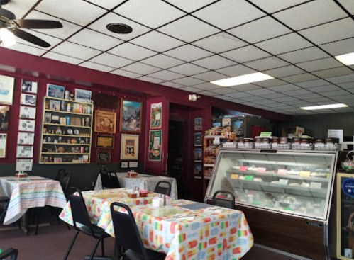 Cozy ice cream shop interior with colorful tablecloths, a display case, and walls adorned with framed memorabilia.